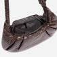 A dark brown shiny Croissant-shaped shoulder bag in polish brown color by Dude & Bestie